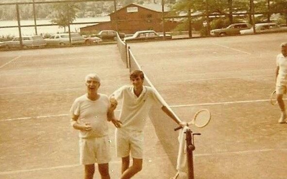 Two men standing in a field with rackets.