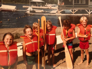 A group of children in life jackets holding paddles.